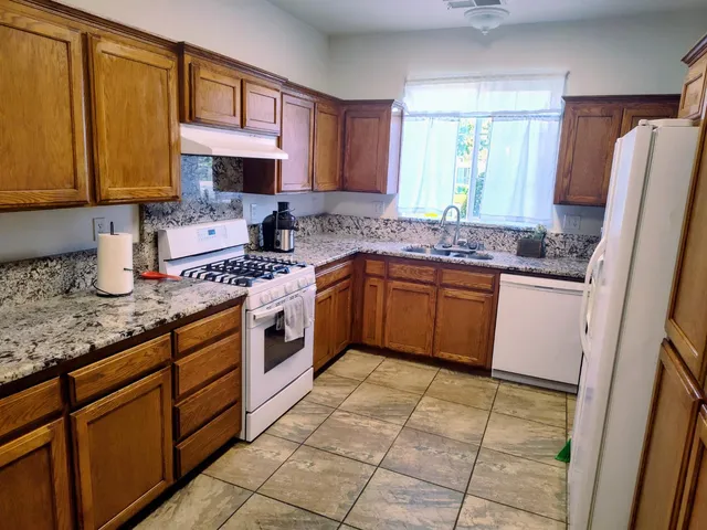 a kitchen with stainless steel appliances granite countertop a sink stove and refrigerator