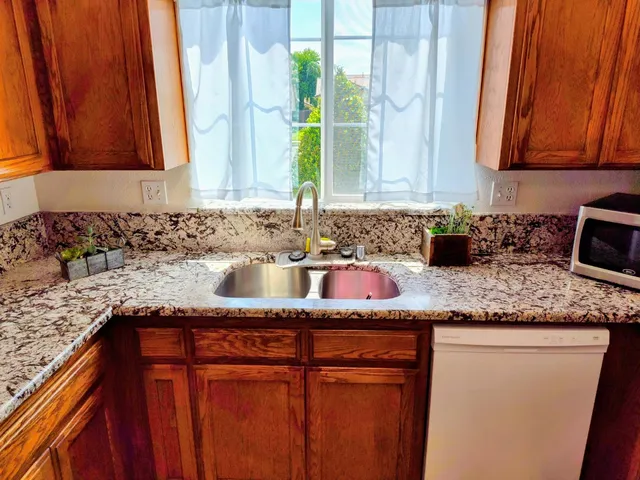 a kitchen with granite countertop cabinets sink and window