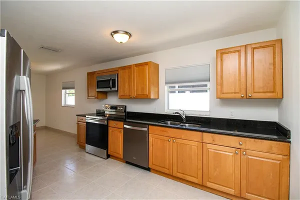 a kitchen with granite countertop cabinets stainless steel appliances a sink and a window