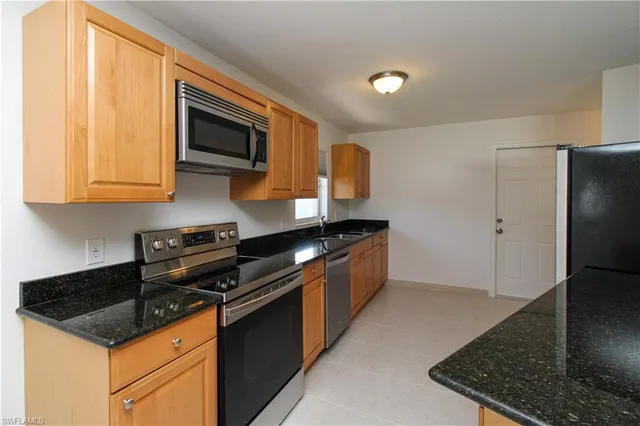 a kitchen with stainless steel appliances granite countertop a stove a sink and a refrigerator