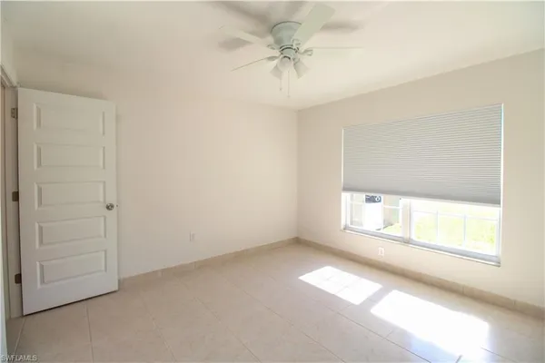 an empty room with windows and ceiling fan