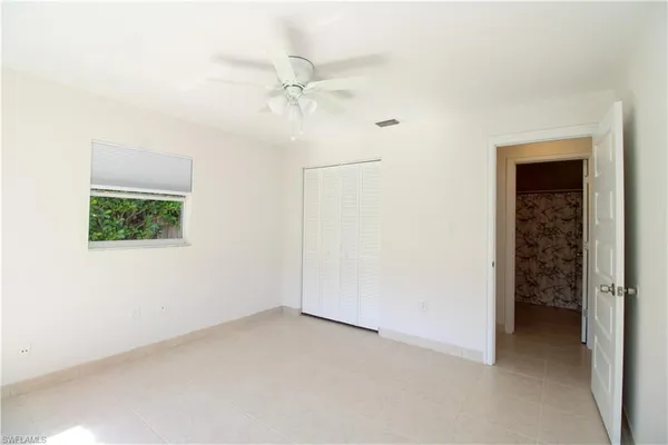 an empty room with a ceiling fan and a window