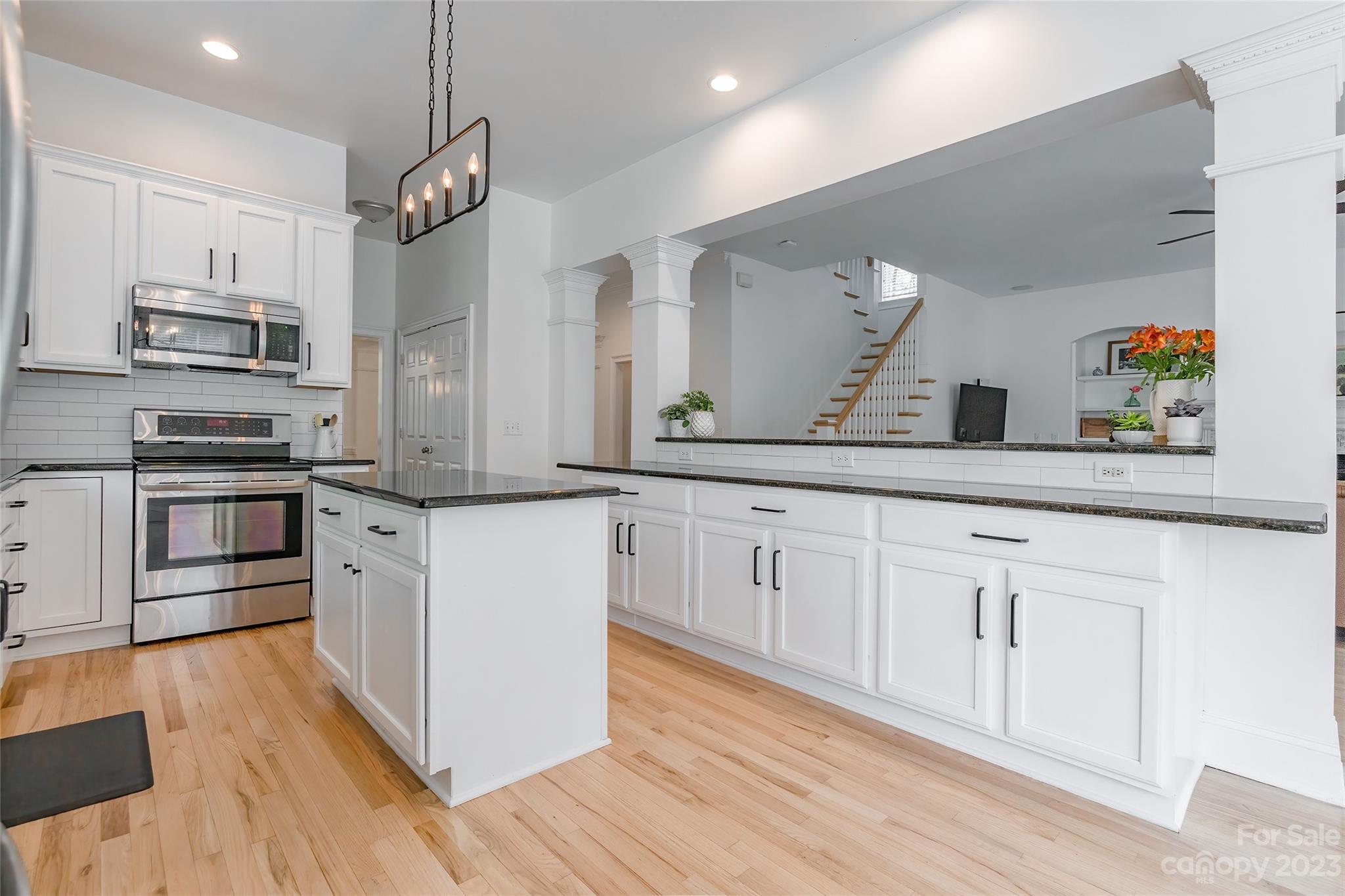 1744 Catherine Lothie Way Fort Mill, SC 29708 - Photo 15 of 44 a kitchen with stainless steel appliances kitchen island granite countertop a stove a sink and white cabinets with wooden floor