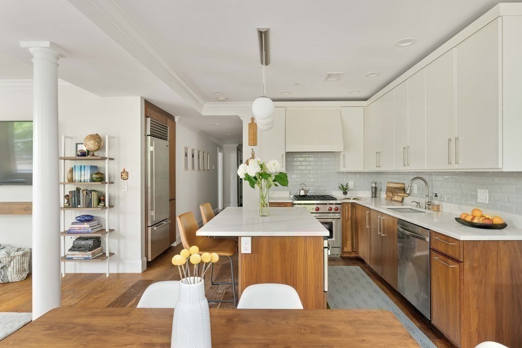 55 Addington Road, Unit 1 Brookline, MA 02445 - Photo 5 of 33 a room with stainless steel appliances kitchen island granite countertop a table chairs in it and white cabinets