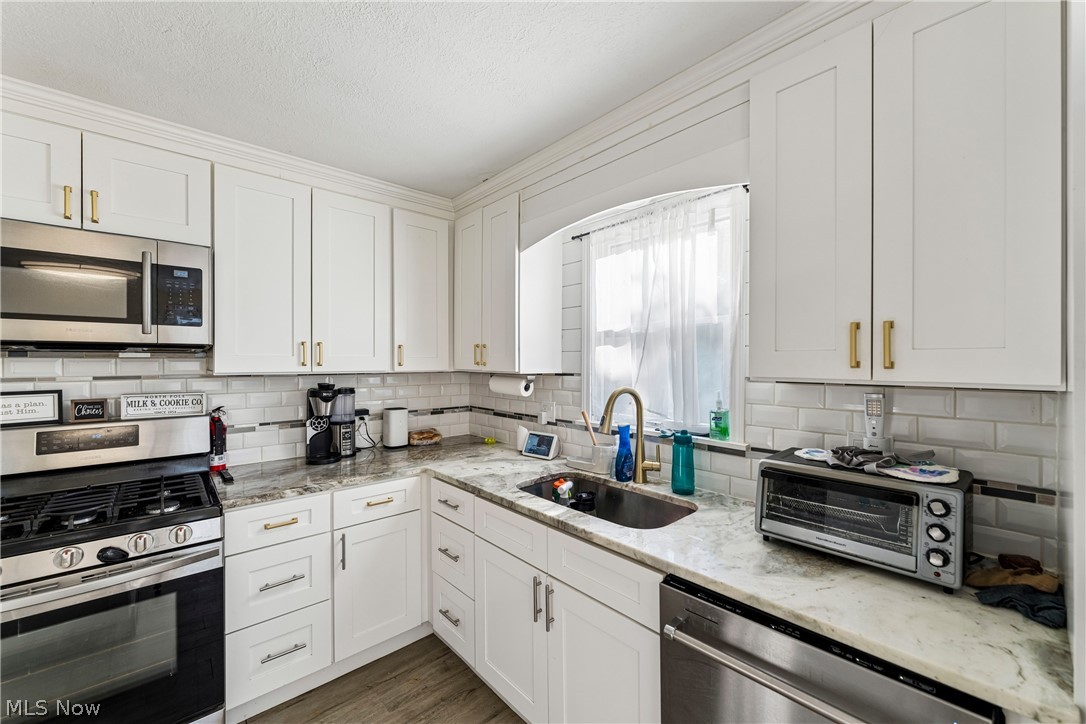 6711 Norwalk Road Medina, OH 44256 - Photo 10 of 46 Eat-in kitchen with white cabinetry, sink, stove, microwave, dishwasher, refrigerator, and center island