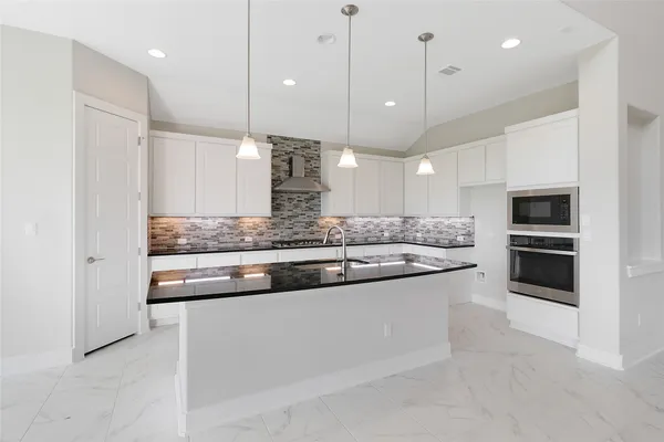 a kitchen with granite countertop a sink a counter top space appliances and cabinets
