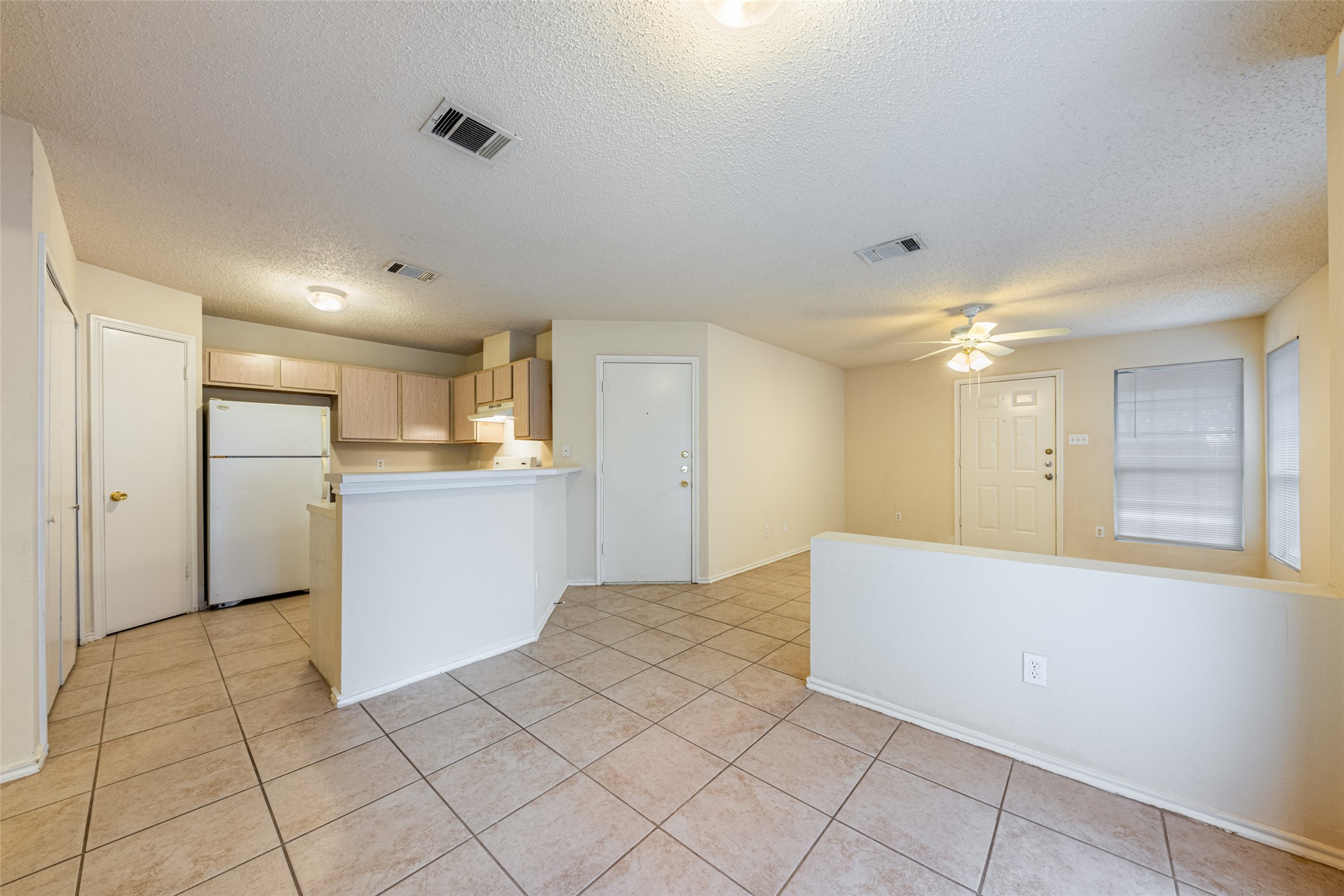 7216 Aldea Drive, Unit A Austin, TX 78745 - Photo 7 of 25 Open-concept living area with neutral tile flooring, a half-wall partition, and a ceiling fan