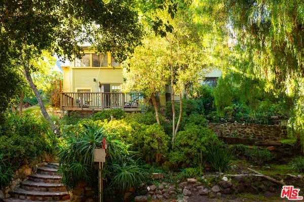 a front view of a house with plants and trees