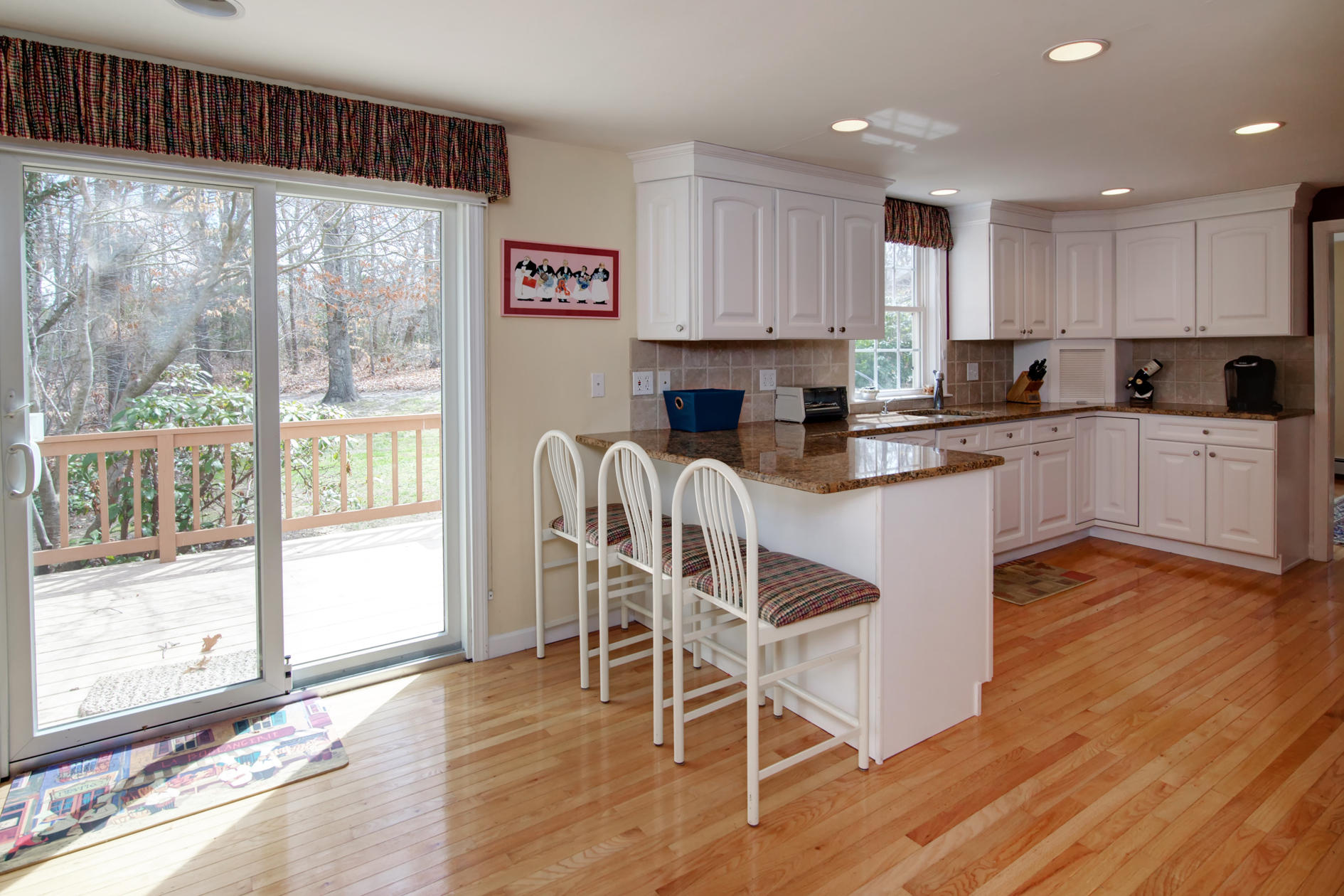 115 Holly Point Road Centerville, MA 02632 - Photo 17 of 26 a kitchen with stainless steel appliances granite countertop a stove top oven a sink and white cabinets with wooden floors