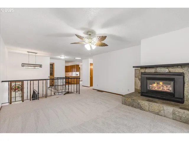 a view of an empty room with a fireplace and a fan