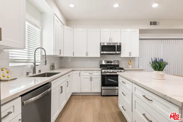 a kitchen with stainless steel appliances granite countertop a table chairs microwave and sink