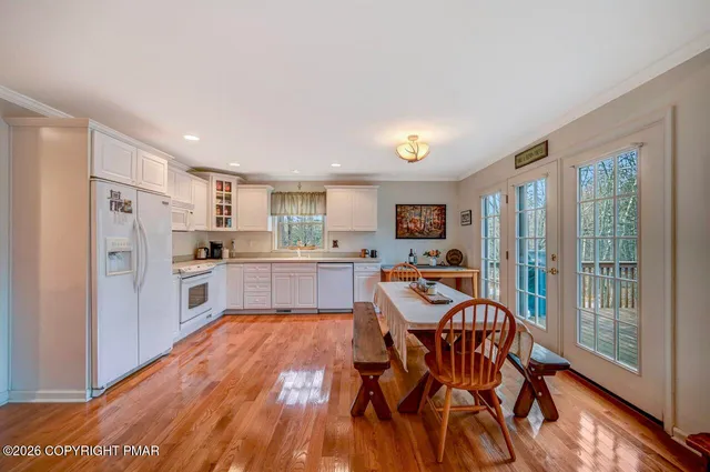 a kitchen with stainless steel appliances kitchen island granite countertop a refrigerator a stove a sink dishwasher with a dining table and chairs with wooden floor