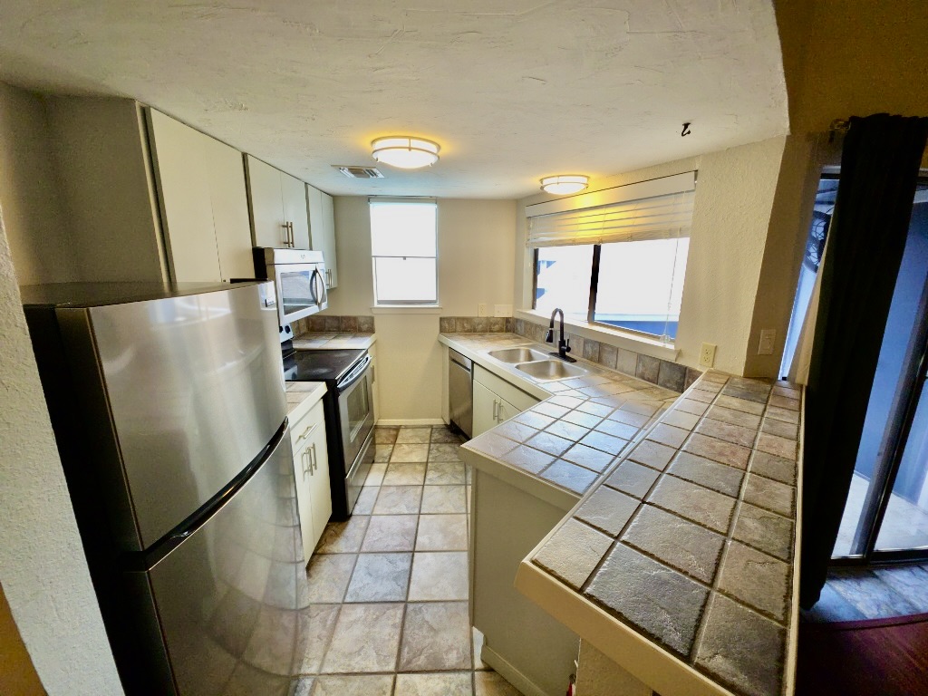 2500 Burleson Road, Unit 521 Austin, TX 78741 - Photo 7 of 20 Kitchen featuring a full suite of stainless steel appliances, tile flooring, tile countertops, and recessed lighting