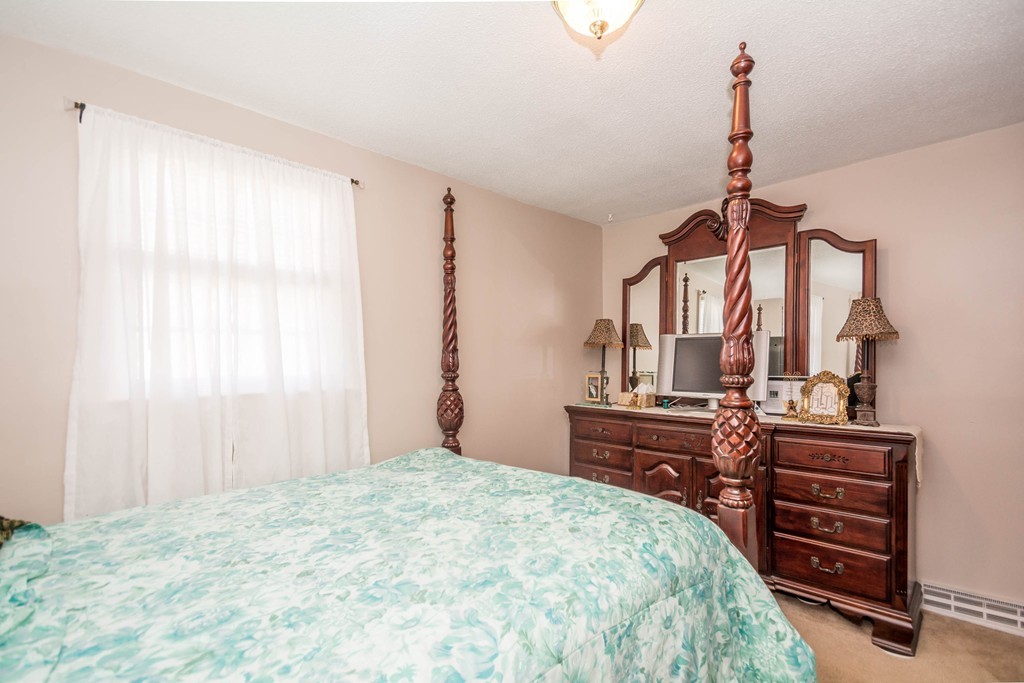 52 Westwind Road Lowell, MA 01852 - Photo 14 of 28 a bedroom with a bed a dresser and potted plants