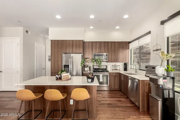 a kitchen with stainless steel appliances granite countertop a table chairs sink refrigerator and cabinets