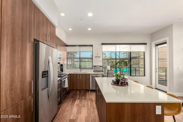 a kitchen with stainless steel appliances granite countertop a refrigerator a sink a stove and white cabinets with wooden floor