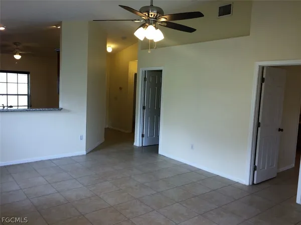 a view of an empty room and window and chandelier fan