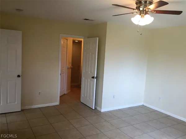 an empty room with closet and a chandelier fan