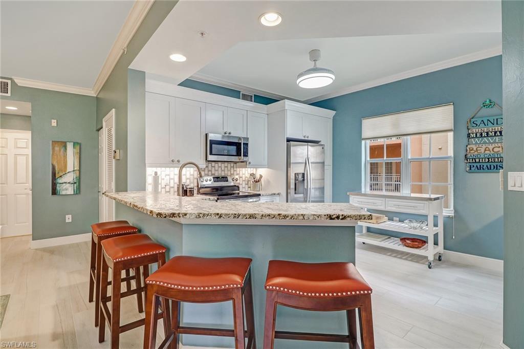 401 Bayfront Place, Unit 3208 Naples, FL 34102 - Photo 4 of 22 a kitchen with stainless steel appliances granite countertop a stove top oven a sink dishwasher a dining table and chairs with wooden floor