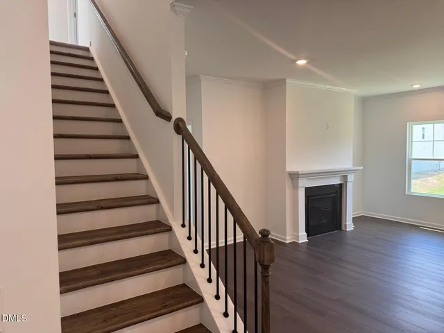 a view of an empty room with wooden floor fireplace and windows