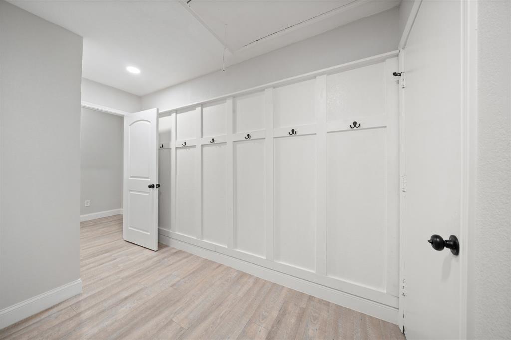 310 Valley Spring Drive Arlington, TX 76018 - Photo 11 of 24 Built-in board and batten wall with integrated hooks, light wood-finish flooring, recessed lighting, and white trim