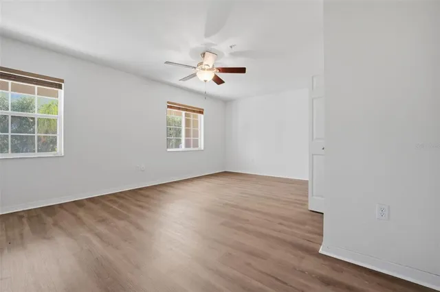 a view of empty room with wooden floor and fan