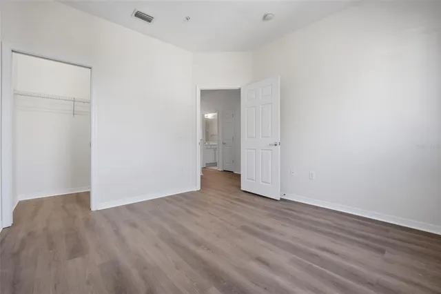 a view of an empty room with wooden floor and closet