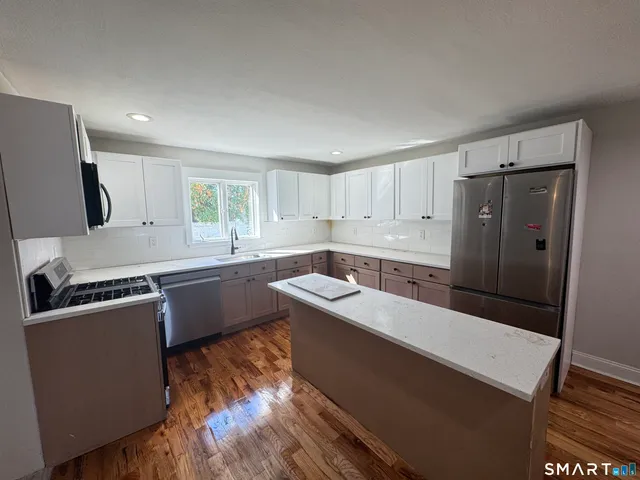 a kitchen with a sink a refrigerator and wooden floor