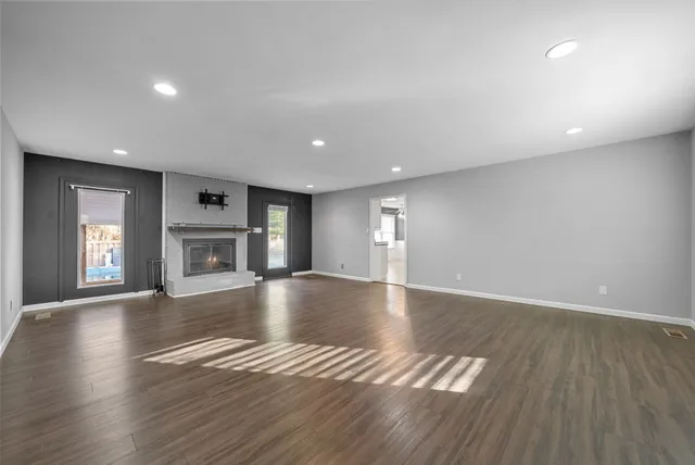 a view of empty room with wooden floor and fireplace