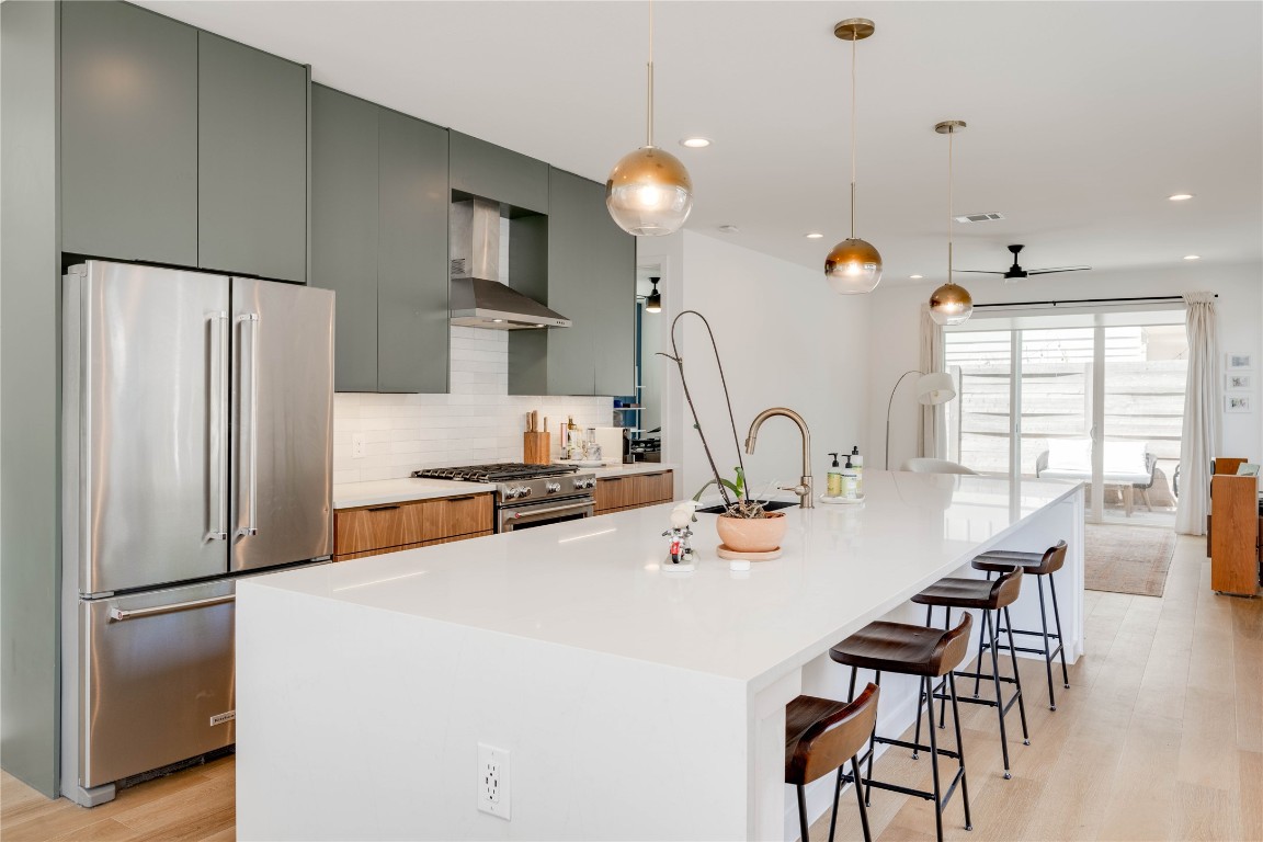 1208 Luna Street, Unit 1 Austin, TX 78721 - Photo 3 of 37 a kitchen with stainless steel appliances a refrigerator a stove a dining table and chairs with wooden floor