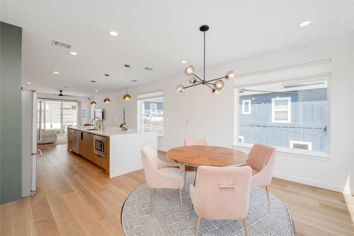 1208 Luna Street, Unit 1 Austin, TX 78721 - Photo 9 of 37 a kitchen with stainless steel appliances kitchen island granite countertop a table chairs in it and wooden floors