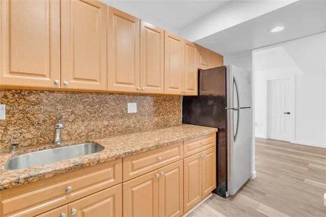 a kitchen with stainless steel appliances granite countertop a sink a refrigerator and a granite counter tops
