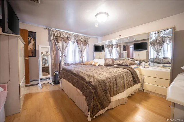 a spacious bedroom with a bed and a large mirror with wooden floor