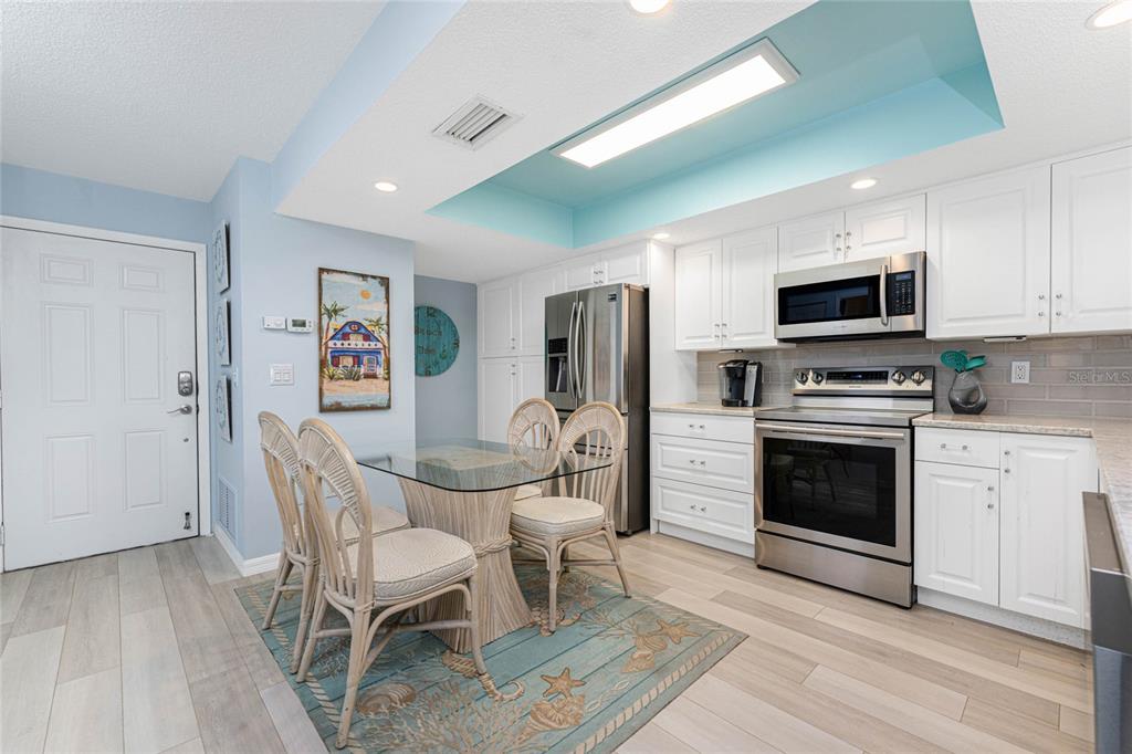 5031 North Beach Road, Unit 222 Englewood, FL 34223 - Photo 4 of 64 a kitchen with stainless steel appliances a stove a sink refrigerator and a dining table with wooden floor