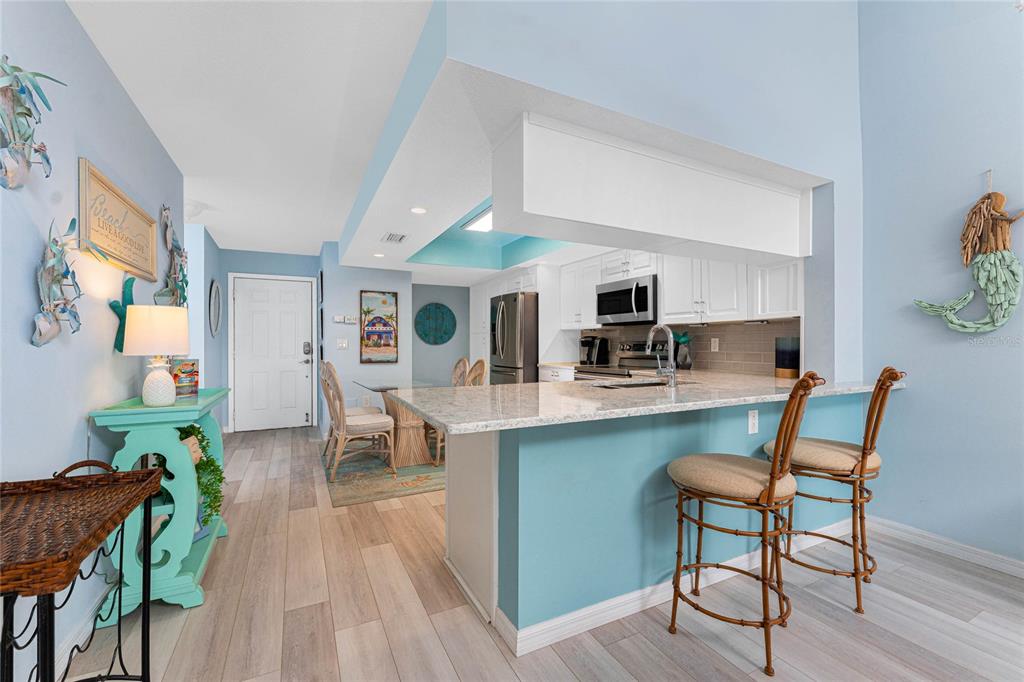 5031 North Beach Road, Unit 222 Englewood, FL 34223 - Photo 9 of 64 a living room with furniture a dining table and chairs with kitchen view