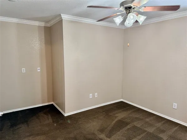 an empty room with a chandelier fan and wooden floor
