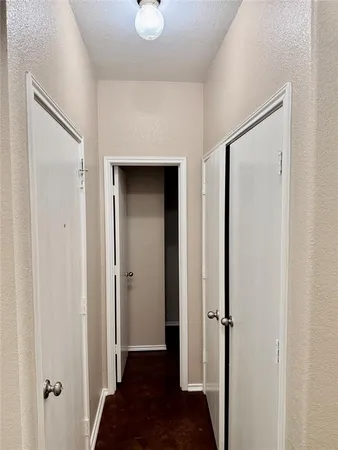 a view of a hallway with a door and wooden floor