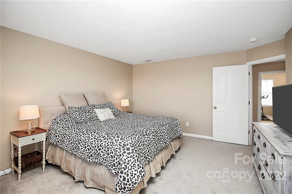 7589 Bluff Point Lane Denver, NC 28037 - Photo 23 of 36 a bedroom with a bed and a flat tv screen on dresser