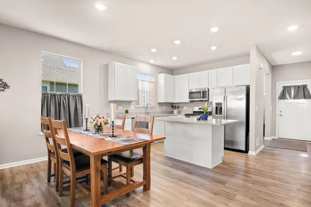 a kitchen with a dining table chairs and refrigerator