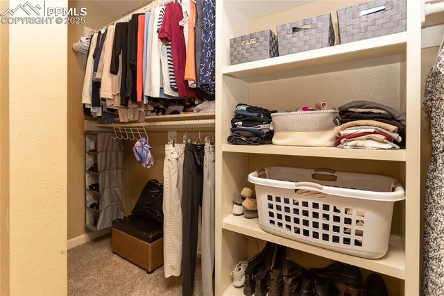 a view of walk in closet with clothes and shoes