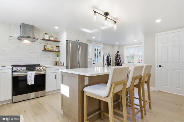 a kitchen with stainless steel appliances kitchen island granite countertop a table chairs sink and cabinets
