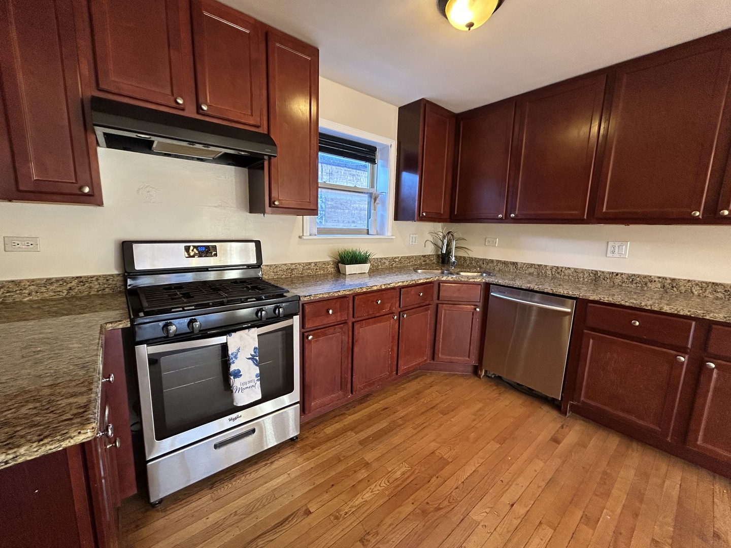 4342 North Kedvale Avenue, Unit 2A Chicago, IL 60641 - Photo 10 of 23 a kitchen with stainless steel appliances granite countertop wooden cabinets a stove a sink and dishwasher with wooden floor