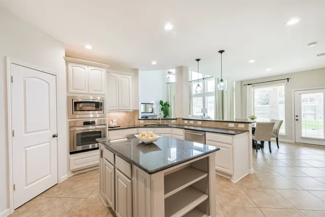 a kitchen with kitchen island granite countertop a sink counter top space appliances and cabinets