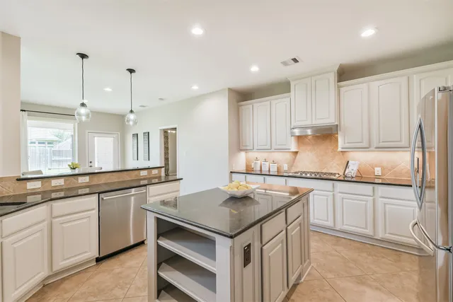 a kitchen with granite countertop sink stove and white cabinets