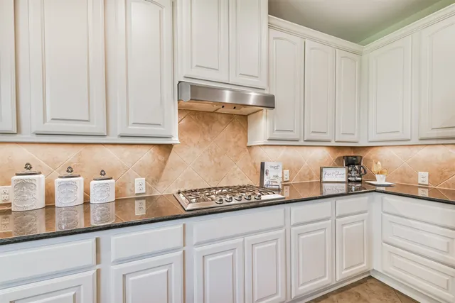 a kitchen with granite countertop white cabinets and a sink