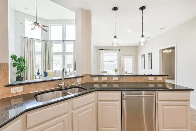 a kitchen with granite countertop a sink a white cabinets and a large window