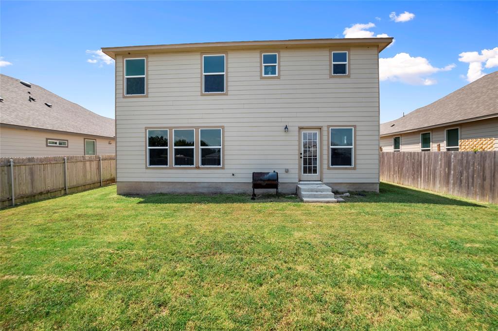 117 West Point Way Elgin, TX 78621 - Photo 18 of 21 A spacious grassy lawn stretches behind this two-story home framed by wood fencing.
