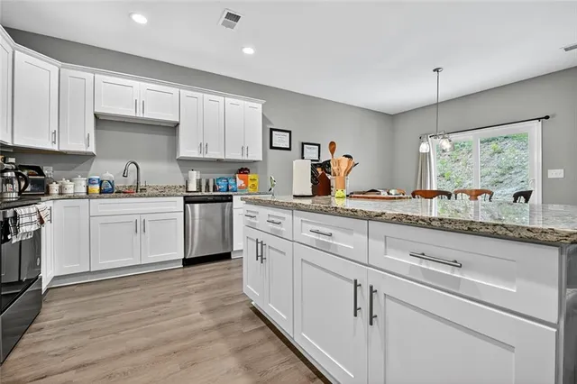 a kitchen with granite countertop white cabinets white appliances and sink