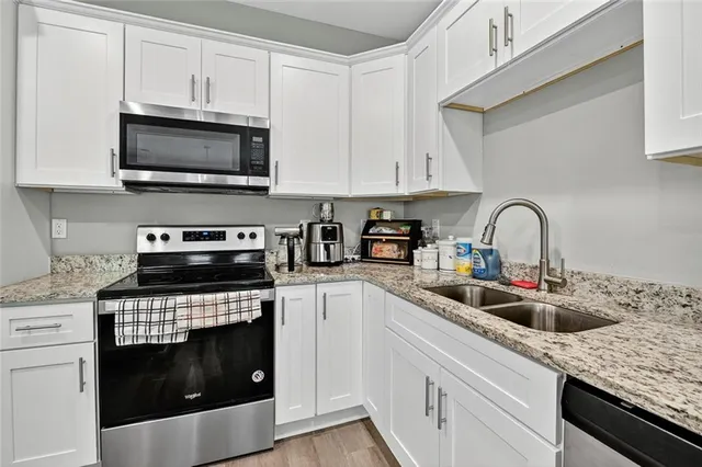 a kitchen with stainless steel appliances granite countertop a sink a stove a microwave and cabinets
