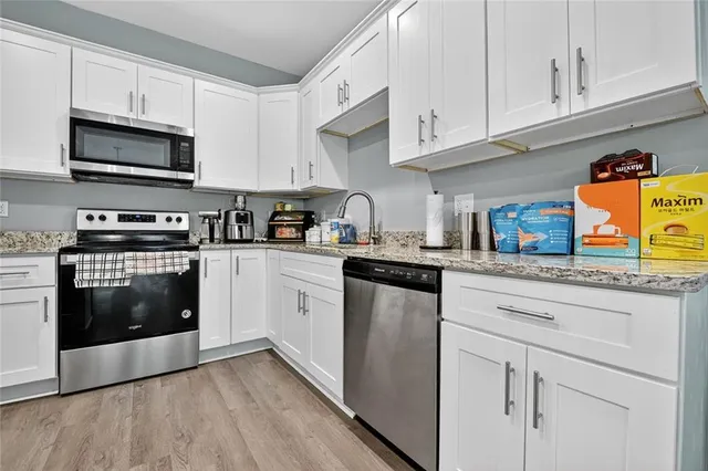 a kitchen with stainless steel appliances granite countertop a stove a sink and white cabinets